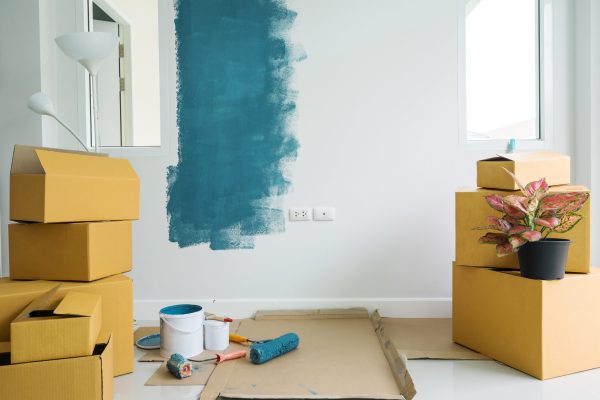 Stack of cardboard boxes and painting equipment in new home with copy space